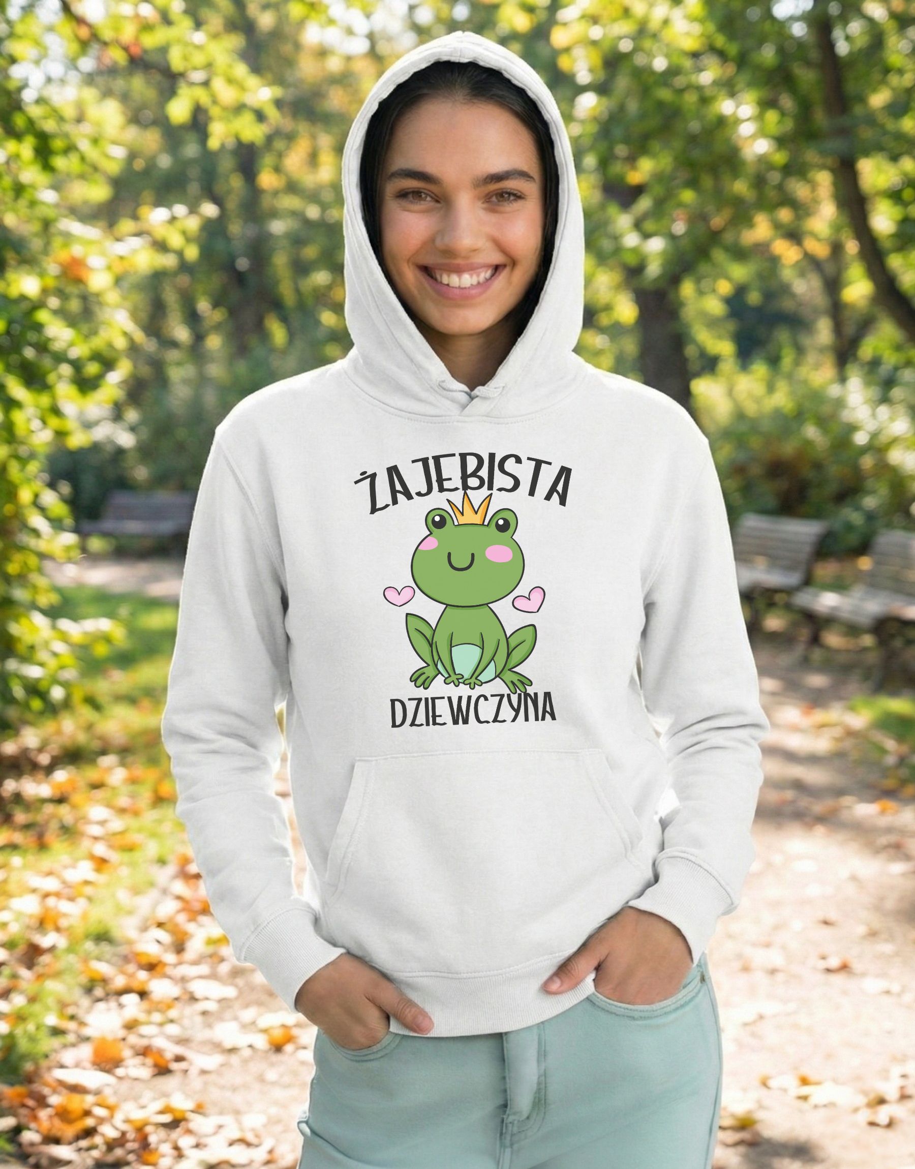 bluza-dla-dziewczyny-z-kapturem-zajebista-biala-model-2 biała bluza dla dziewczyny z grafiką zielonej żabki w złotej koronie i z napisem 'Żajebista dziewczyna' zaprezentowana na modelce